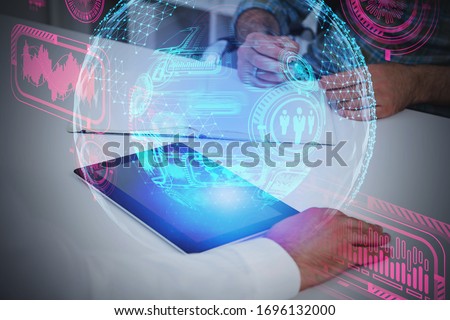 Businessmen hands working with tablet at blurry office table with double exposure of creative futuristic HUD business interface. Concept of hi tech and coding. Toned image