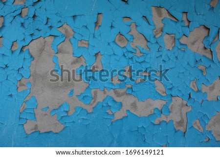 blue paint on the wall. gray concrete wall painted. old paint is peeling off.
