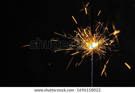 Burning sparkler, on a black background with copyspace, happy new year