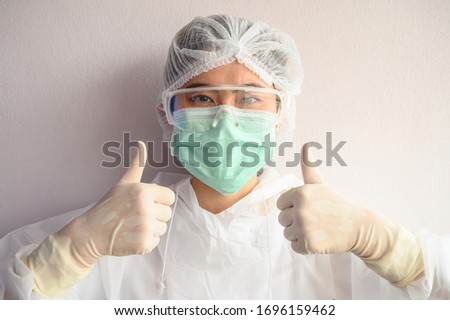 Nurse wearing PPE suit with mask for protect virus and showing thumbs up. In coronavirus pandemic outbreak we should support and encourage healthcare worker by stay home and listen to medical advice. Royalty-Free Stock Photo #1696159462
