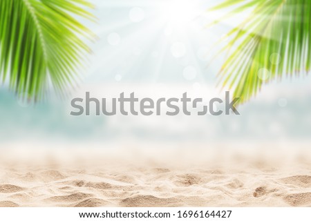 Blurred blue sky and sea with bokeh light and leaves of coconut palm tree. Landscape of tropical summer. Summer vacation concept.