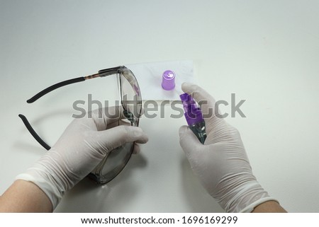 Staff wearing medical glove and cleaning protection glasses with alcohol spray. Avoid infected corona virus and bacteria from touching public object.   Royalty-Free Stock Photo #1696169299