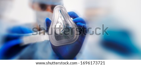 Doctor puts on oxygen mask to connect a patient losing consciousness to an artificial respiration device. Royalty-Free Stock Photo #1696173721