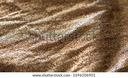 wavy rich metallic gold foiled fabric background with shinny reflective cracked surface