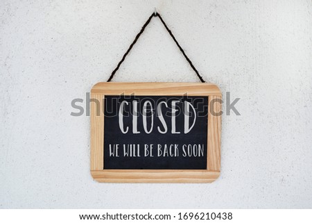 a wooden-framed chalkboard, with the text closed, we will back soon written in it, hanging from a white wall