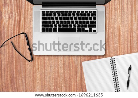 Top view wood table of laptop with cell phone, glasses, pen, notebook on wood background. of free space for your copy.
