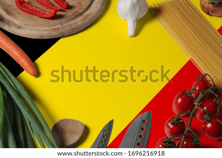 Belgium flag on fresh vegetables and knife concept wooden table. Cooking concept with preparing background theme.