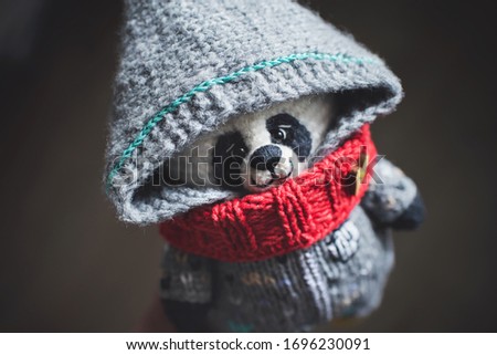 
Handmade knitted toy. Amigurumi panda toy in grey color overalls on the wooden  background. Crochet stuffed animals.