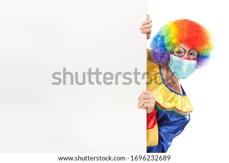 Clown wearing a mask showing a blank panel, coronavirus concept