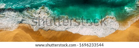 Beautiful sea wave at sunset from a bird's eye view. Beautiful lonely beach at sunset. Aerial view of turquoise ocean waves in Kelingking beach, Nusa penida Island in Bali, Indonesia. Beaches of Bali