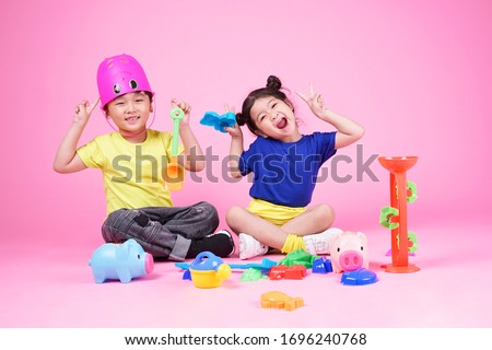 Happy Asian cute little kid boy and girl playing on pink background