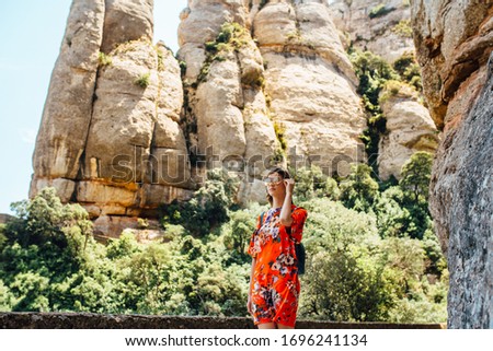 A female traveller enjoys the view from the mountains of Montserrat in Spain. Girl in a red dress against the background of nature