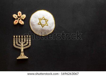 Jewish Kippah Yarmulkes hats with menorah on black wooden table. Top view, copy space