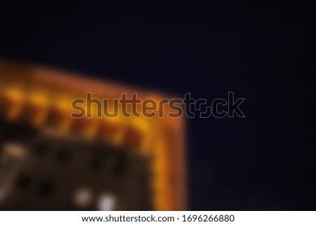 Blurred abstract urban background. The illuminanted top of an old multistory building