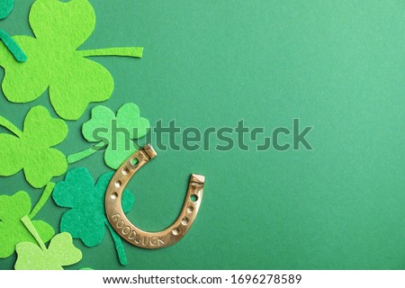 Flat lay composition with clover leaves and horseshoe on green background, space for text. St. Patrick's day Royalty-Free Stock Photo #1696278589
