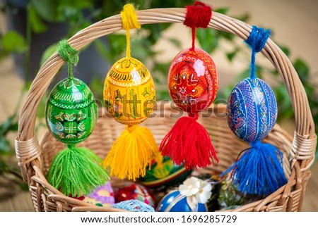 Beautiful, colorful hand painted Easter eggs, made of wood in a brown wicker basket – decoration of a holiday table during celebration