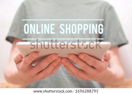 Online shopping - man holding in hands digital tablet with text. Online purchasing and selling,  e-commerce concept.
