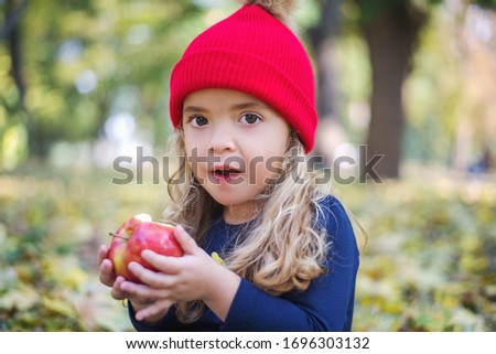 Cute little girl eating an apple in the park