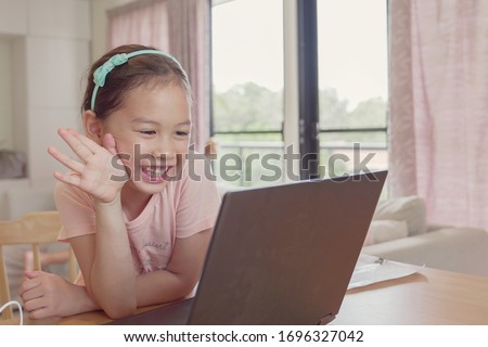 Girl making facetime video calling with laptop at home, using zoom  online virtual class , social distancing,homeschooling,learning remotely during covid coronavirus pandemic, new normal concept Royalty-Free Stock Photo #1696327042