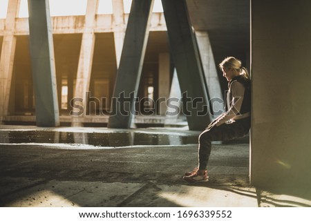 Young Caucasian woman taking a exercises break, leaning on the wall
