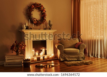 Cosy living room with decor. Cozy fireplace with armchair. Interior in a cozy house