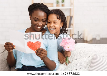 Happy Mother's Day Concept. Black child greeting her mom with flowers and card, copyspace Royalty-Free Stock Photo #1696378633