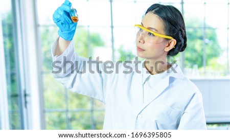 Professor asian woman researcher white gown look at testing chemical liquid with face concentrating. With background interior white laboratory.