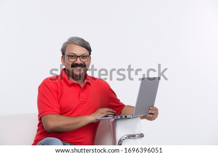 Relaxed man using laptop while sitting on sofa