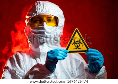 health, medicine and pandemic concept - female doctor holding boihazard caution sign.