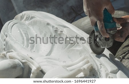 Professional stone carver using grinding tool to shape white marble and create unique Burmese Buddha statues, Burma's unique art in Mandalay,Myanmar Royalty-Free Stock Photo #1696441927