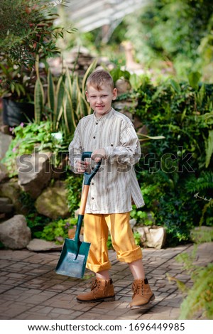 The boy works in a beautiful green garden.
