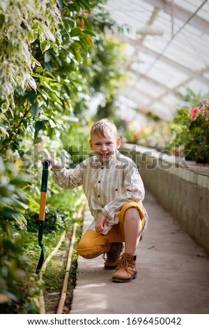 The boy works in a beautiful green garden.