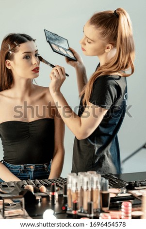 makeup artist applying concealer on beautiful model