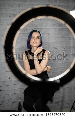 Girl sitting in front of a ring light in a beauty salon. Makeup artist, hair stylist space.