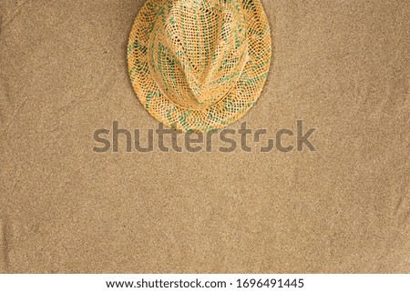 Straw hat on sand background