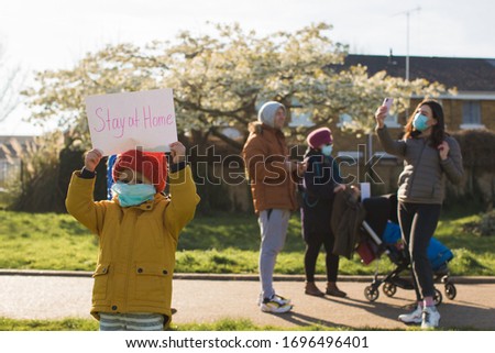 child at park on quarantine with stay at home sign and people on background