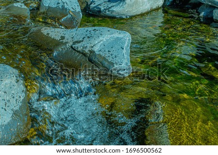 Large river stones in the river. Clear tea.
