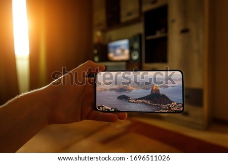 Concept of travel on a smartphone. Stay at home tourism. Online travel to Rio-De-Janeiro. Sugarloaf on a screen.