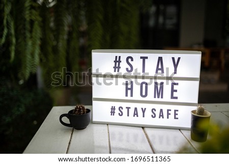 Lightbox sign with text hashtag #STAY HOME and #STAY SAFE with cactus pot home decor. COVID-19. Stay home safe concept.