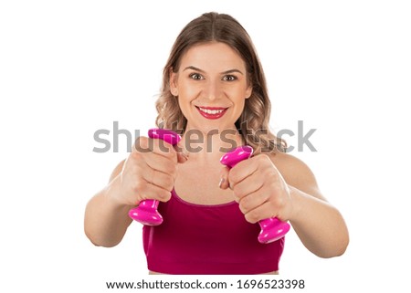 Attractive sporty woman holding pink dumbbells is smiling to the camera on isolated background