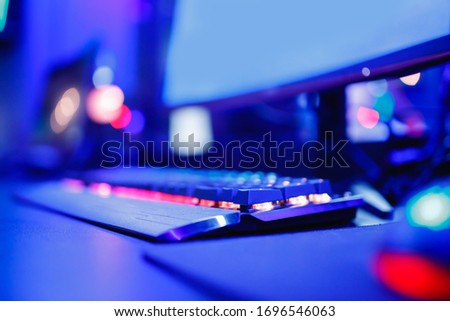 Blurred background professional gamer playing tournaments online games computer with headphones, red and blue.