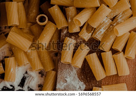 Raw pasta placed out on the kitchen surface with flour eggs and tomatoes on the wooden background
