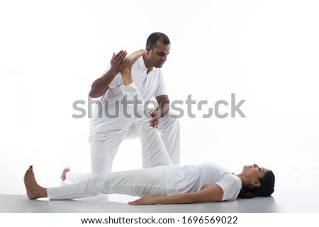 Male yoga instructor guiding yoga at studio over white background.
