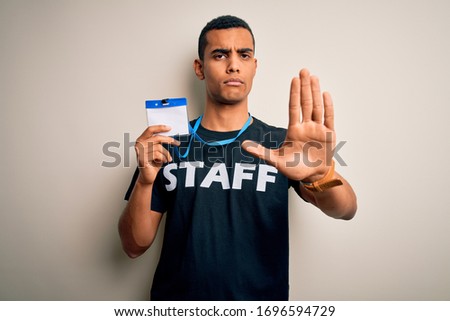Young handsome african american worker man wearing staff uniform holding id card with open hand doing stop sign with serious and confident expression, defense gesture