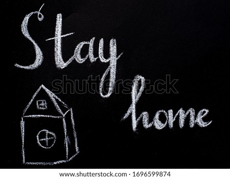 Drawing with chalk on a black blackboard, house and text Stay Home. Concept of virus protection