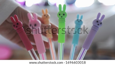 Bright colored pens with rabbits. Children's hand touches colored pens.