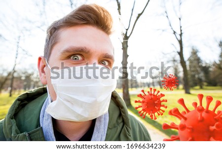 Portrait of a man with medical mask on a city public park background. Coronavirus pandemic. Concept Of Air pollution, Pneumonia Outbreak, smog or Epidemic. Red virus strain model of covid-19 in the air