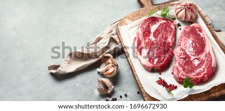 Raw beef steaks on wooden cutting board. Image with copy space