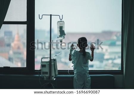 Child patients in the hospital are adding saline solution on hand , stand at the window to look out. Royalty-Free Stock Photo #1696690087