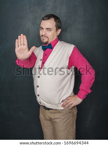 Funny teacher or business man with stop gesture on blackboard background